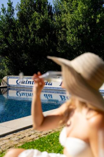 a woman wearing a straw hat sitting next to a pool at Vinte-Quinta da Boavista in Ponte de Lima
