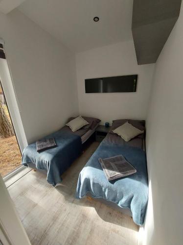 a room with two beds and a tv on the wall at Domki Bliżej Gwiazd in Krasnobród
