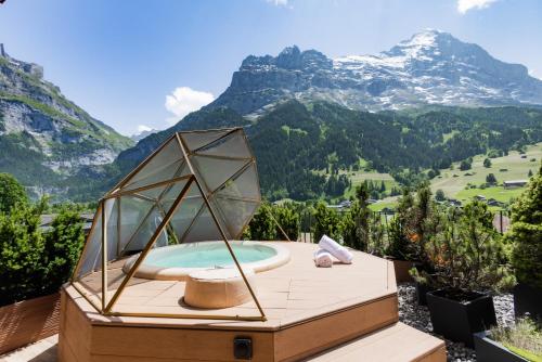 a hot tub on a deck with mountains in the background at Boutique Hotel Glacier in Grindelwald