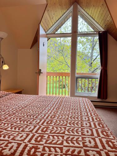 a bedroom with a bed and a large window at Auberge du Jardin in Petit-Saguenay
