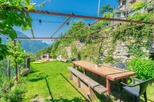 a wooden table and chairs in a garden at Casa Minù in Faggeto Lario 