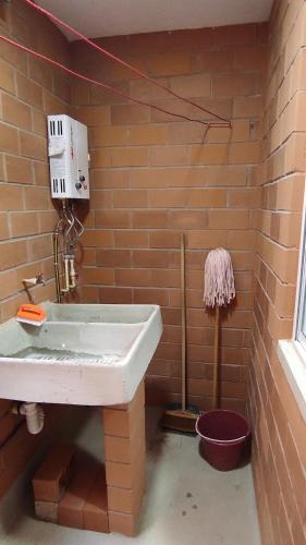 a bathroom with a white sink and a brick wall at Depa Risalud! in Santa Cruz Huatulco