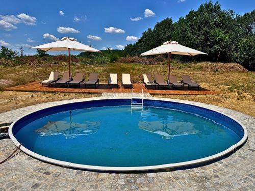 a small swimming pool with chairs and umbrellas at Геша Форест in Dryanovo