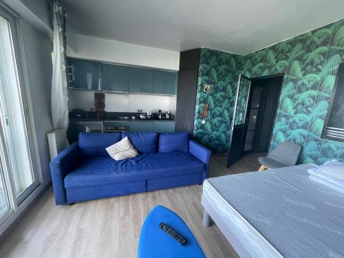 un salon avec un canapé bleu et une cuisine dans l'établissement Studio sur 2 plages , piscine et 3 personnes, à Biarritz