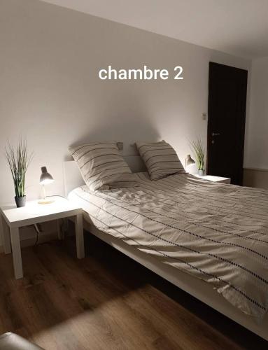 a bed in a white room with a table at La randonnée in Beaumont