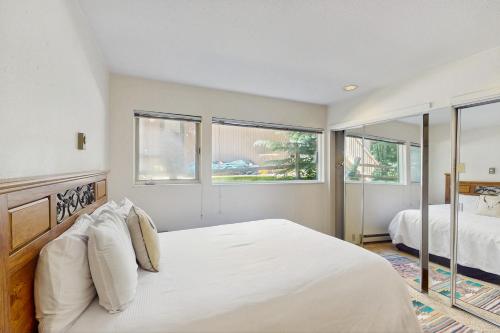 a bedroom with a large bed and two windows at Cozy 1 Bedroom East Vail Condo #2C. Shuttle, Hot Tub, and Market on Site. in Vail