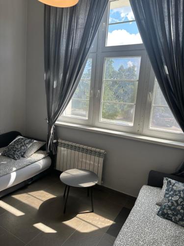 a bedroom with two beds and a chair in front of a window at Apartament Bankowy in Olecko