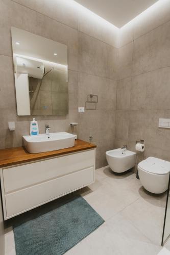 a bathroom with a sink and a toilet and a mirror at MIKU Green Coast in Palasë