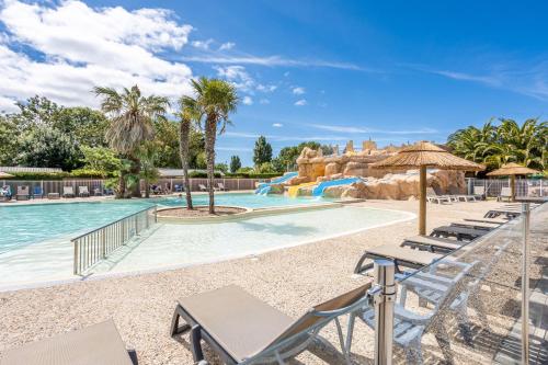 - une piscine avec des chaises et un toboggan dans un complexe dans l'établissement Mobilhome 4 personnes Ile d'Oleron, à Saint-Denis-dʼOléron