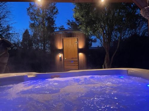 a jacuzzi tub at night with a wooden door at Wellness Bungalow Bolder 5p Amsterdam and the beach in Opmeer