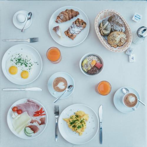 a table with plates of breakfast foods and coffee at Hotel Traube in Bressanone