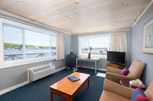 a living room with a couch and a table and a tv at Fisherman's Wharf Inn in Boothbay Harbor