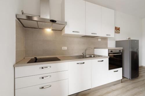 a kitchen with white cabinets and a stainless steel refrigerator at Agriturismo Le Macere in Sasseta