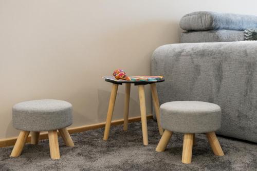 a table and two stools next to a couch at Duma Apartmani 2 Vrnjačka Banja in Vrnjačka Banja