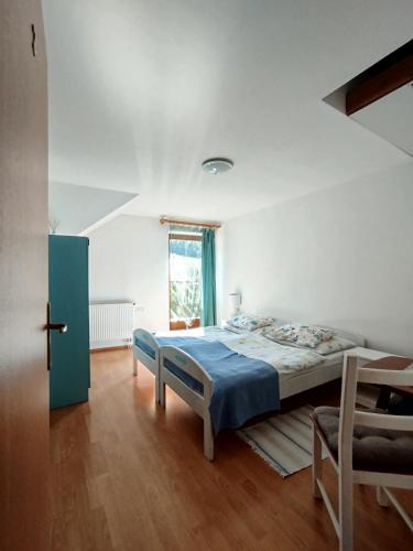 a bedroom with a bed with a blue blanket and a window at Chata Holica PIENINY in Lesnica