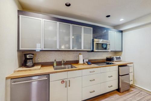 a kitchen with white cabinets and a sink and a microwave at Gore Creek Condo in Vail