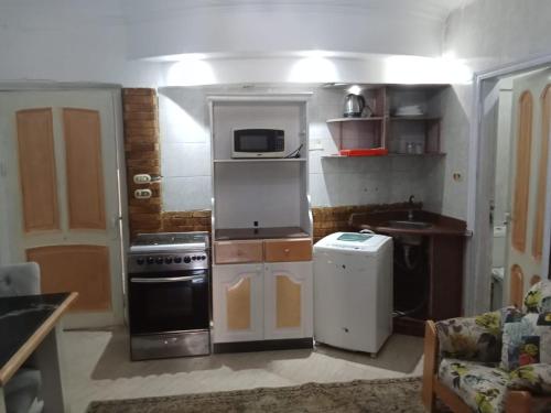 eine kleine Küche mit Herd und Mikrowelle in der Unterkunft First floor chalet 4 VILLA 114 2bed rooms and 2 bathrooms Green Beach in El-Alamein