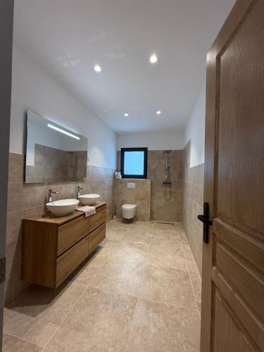 a bathroom with two sinks and a toilet and a television at Chez Claudine & Adrien in Figari