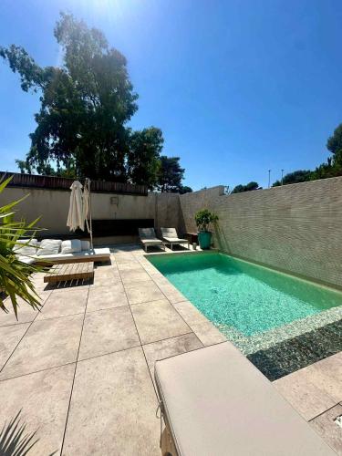 - une piscine avec des chaises longues à côté d'un mur dans l'établissement Sublime villa vue mer pieds dans l'eau, à Monticello