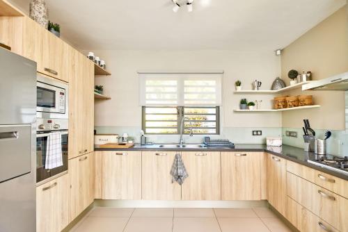 a kitchen with wooden cabinets and a sink at SG17 Villa Sable Front de Mer in Palmar