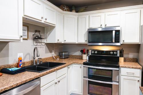 a kitchen with white cabinets and a sink and a microwave at Lakefront Captains Quarters - 31 in Mead