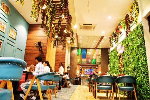 a restaurant with people sitting at tables and plants at Hotel 7-B in Chhatarpur