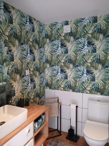a bathroom with a toilet and a green leafy wallpaper at Andaluzja - La casa de Dejna in Ventas del Carrizal