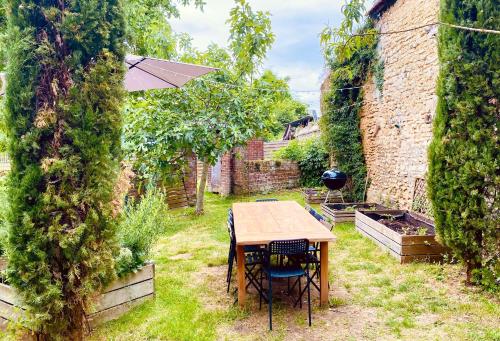 a table and chairs in a garden with an umbrella at Le Gîte de Little Castle campagne à 1 h de Paris in Trie-Château
