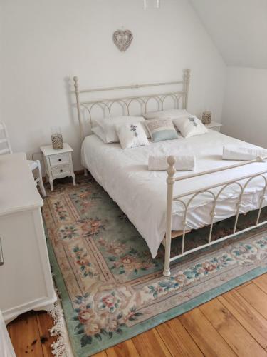 - une chambre avec un lit blanc et un tapis dans l'établissement Cottage Lavandes et Cottages Roses, à Crédin
