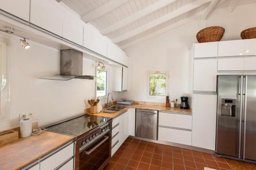 a kitchen with white cabinets and a stainless steel refrigerator at The Beach Bungalow Sisters in Baie Longue