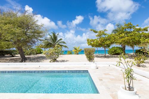 a swimming pool with the beach in the background at The Beach Bungalow Sisters in Baie Longue