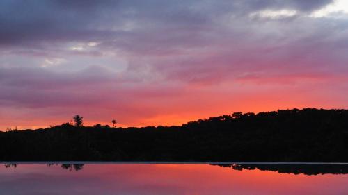 a sunset over a body of water with a forest at Monte do Álamo da Serra in Redondo