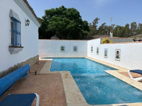 a swimming pool next to a white wall at Casita Bella in Chiclana de la Frontera