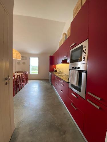 a kitchen with red cabinets and a microwave at Monte do Álamo da Serra in Redondo