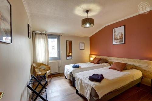 deux lits dans une chambre aux murs orange dans l'établissement La petite plenitude, à Saint-Chamond