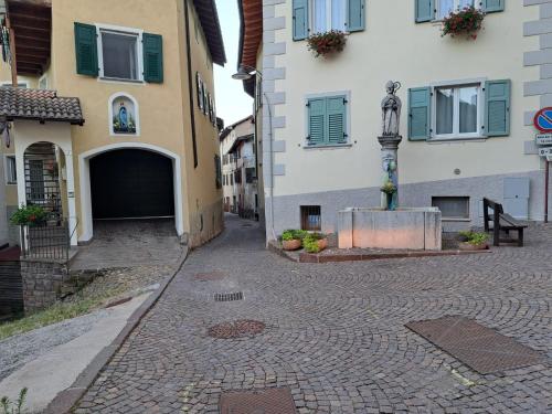 a cobblestone street in front of buildings with a statue at Casa Carraia Monolocale in Cembra