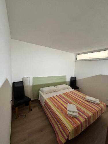 a bedroom with a bed and a chair and a window at Casa Carraia Monolocale in Cembra
