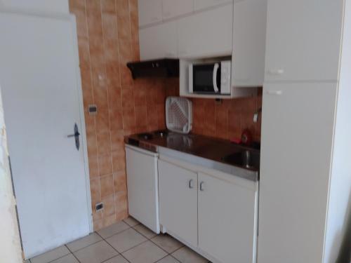 une petite cuisine avec des armoires blanches et un micro-ondes dans l'établissement STUDIO 2 LUZ SAINT SAUVEUR 4 Personnes, à Luz-Saint-Sauveur