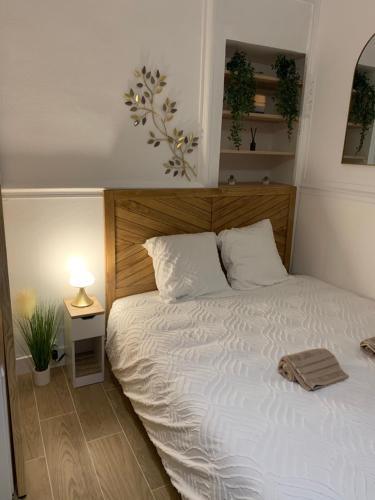 une chambre avec un lit blanc avec une tête de lit en bois dans l'établissement La Suite Bohème, à Poitiers
