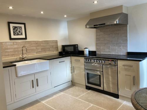 a kitchen with white cabinets and a sink and a stove at Bank Top Barn Double Bedroom Self-catering 2 guests in Pickering