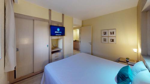 a bedroom with a bed and a tv on the wall at Ambassador Residence Apart-hotel in Curitiba