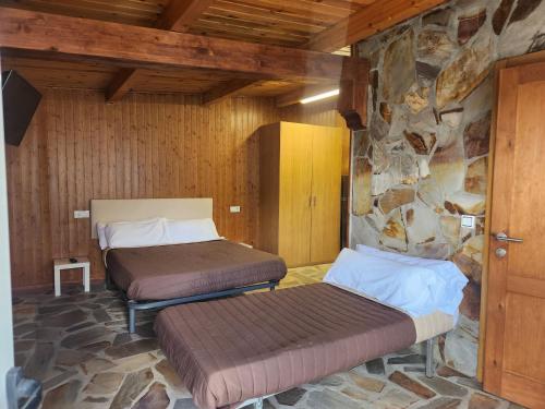 two beds in a room with a stone wall at Casa Jardín in Monforte de Lemos
