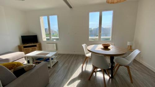 una sala de estar con una mesa y un sofá en Le Hameau, confortable logement avec accès direct à la plage, en Bernières-sur-Mer