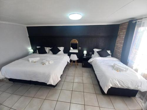 a bedroom with two beds with white sheets at Inni Bush Guesthouse in Noordheuwel