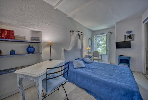 a bedroom with a blue bed and a table at Mas Les Micocouliers in Saint-Christol-lès-Alès
