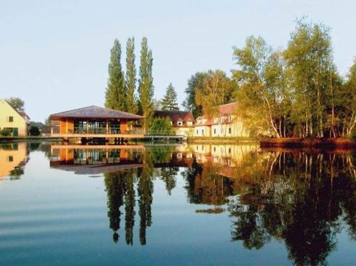 a house on a lake with its reflection in the water at Camping maeva Respire Domaine de Sainte Montaine in Sainte-Montaine
