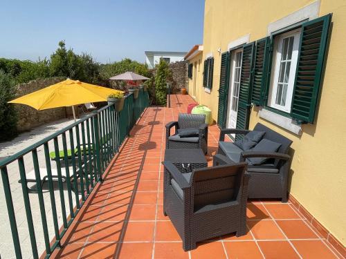 a patio with chairs and an umbrella on a balcony at Elegant Villa Mello with Beautiful Outdoor Area in Lourinhã