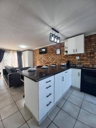 a kitchen with white cabinets and a black counter top at Inni Bush Guesthouse in Noordheuwel