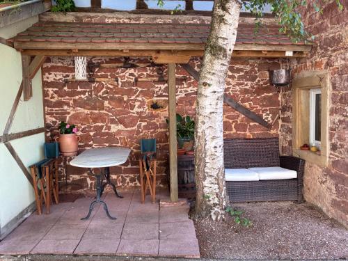 a patio with a table and a bench and a tree at Le Grenier - Piscine et SPA in Marlenheim