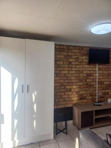 a living room with a white cabinet and a brick wall at Inni Bush Guesthouse in Noordheuwel